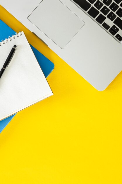 Laptop and notepads on a yellow background flat lay