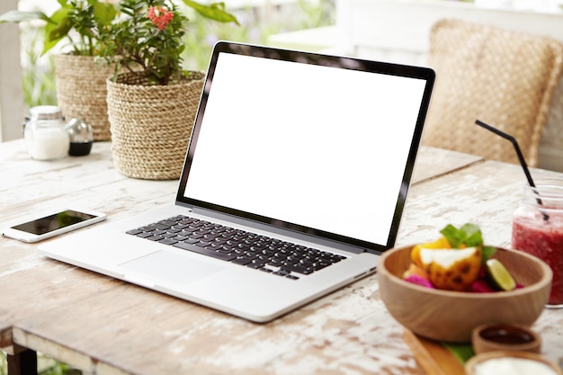 Laptop and other electronics on workspace. Business workplace with modern open laptop and smart phone on wooden table.