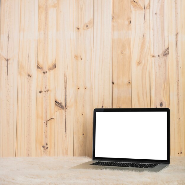 Laptop on soft fur against wooden plank