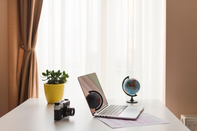 Free photo laptop on table near camera and globe