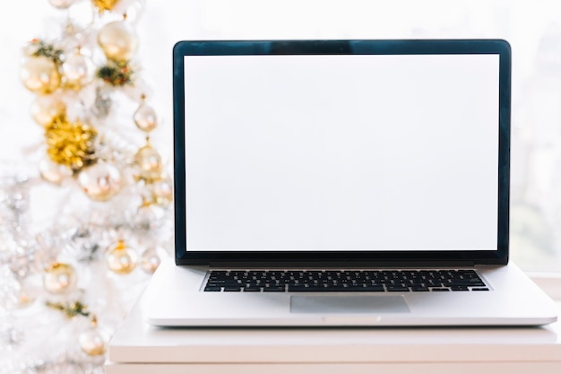 Laptop on table near Christmas tree