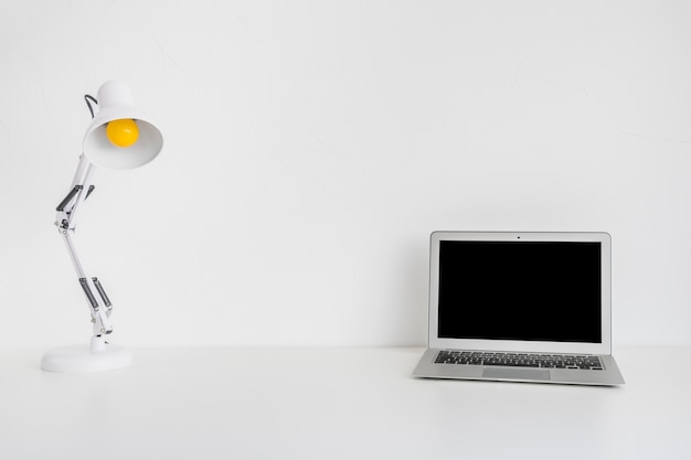 Laptop and white desk lamp on white background