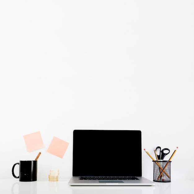 Laptop with blank black screen on desk in office