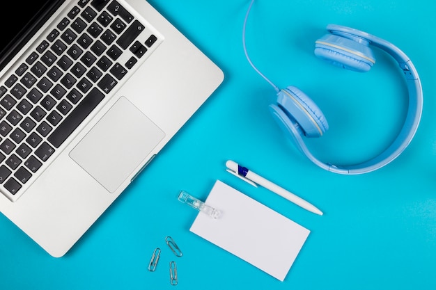 Laptop with blank paper and headphones 