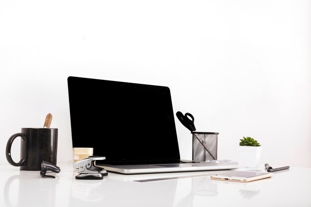 Laptop with blank screen and cellphone on reflective desk