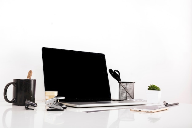 Laptop with blank screen and cellphone on reflective desk