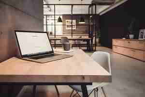 Free photo laptop with blank screen on wooden table in modern office mockup