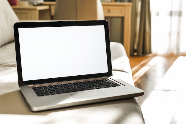 Laptop with blank white screen on sofa at home