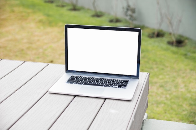 Laptop with blank white screen on wooden desk