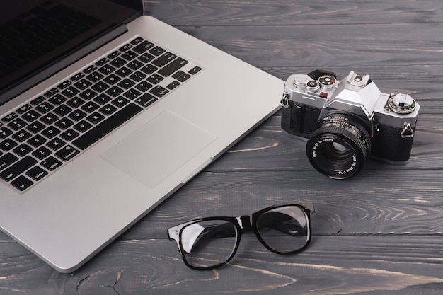 Laptop with camera and glasses on table 