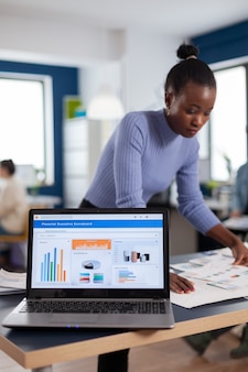 시작 회사와 통계를 읽는 여자의 사무실에 금융 차트가있는 노트북