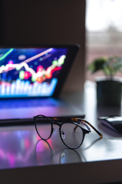 Laptop with graphs and statistics and glasses on the table