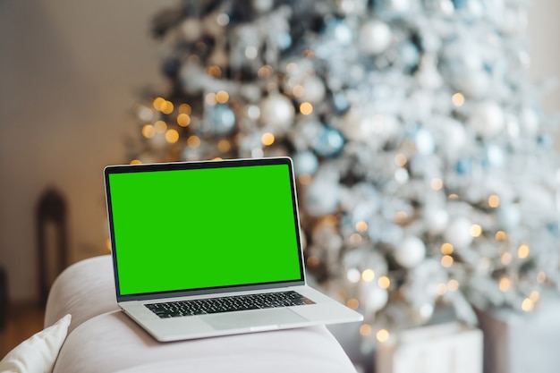 Ноутбук с хромакеем зеленого экрана возле елочных игрушек