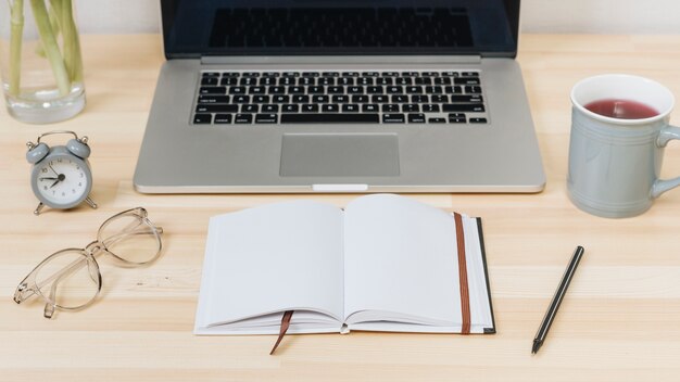 Laptop with notebook on wooden table