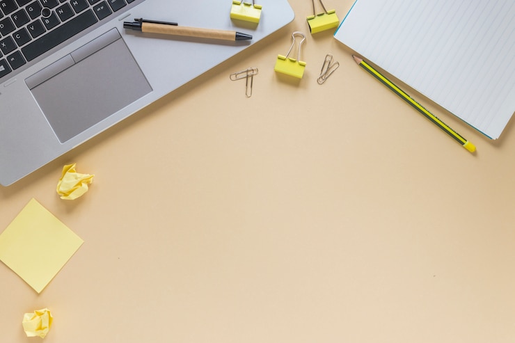 Free Photo laptop with pen; pencil; paper clips; sticky notes and spiral notepad on beige background