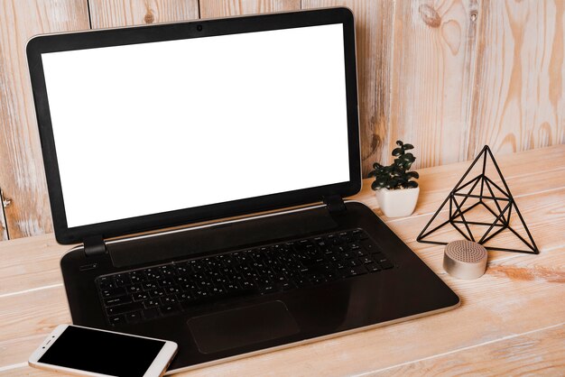 Laptop with white blank screen and smart phone on wooden table