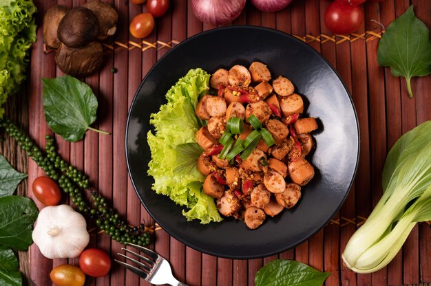 Larb Sausage with Chili Spring onions and lettuce in a black plate