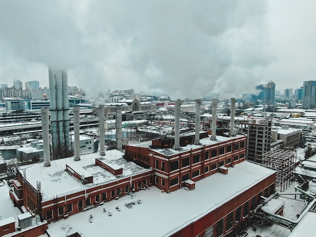 Foto gratuita grande centrale termica con tubi giganti di cui c'è fumo pericoloso in inverno durante il gelo in una grande città