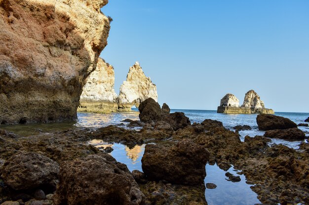 Large cliffs sticking out of the water during daytime in Lagos, Portugal