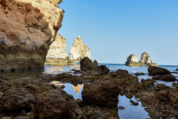 Большие скалы, торчащие из воды в дневное время в Лагуше, Португалия