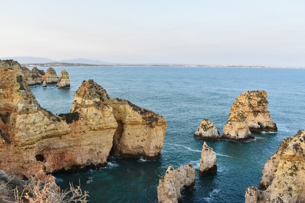 Large cliffs sticking out of the water during daytime in Portugal