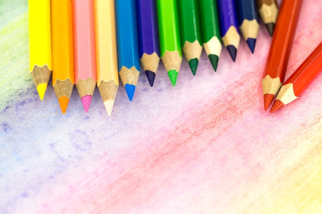 色鉛筆で色付きの背景に大きな色鉛筆のクローズアップ