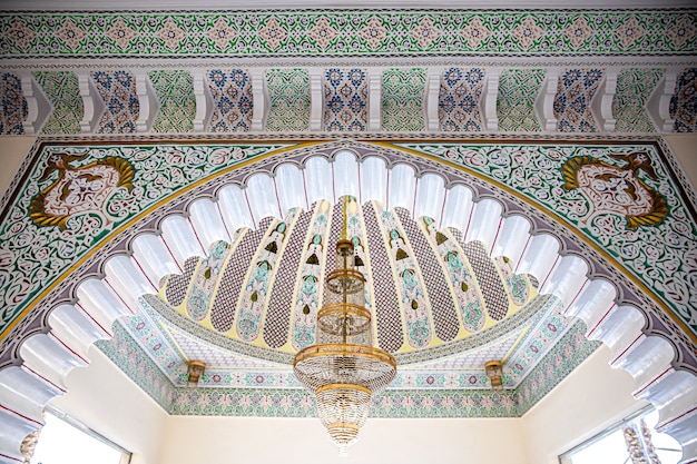 Foto gratuita grande lampadario dorato su un soffitto variegato con ornamento religioso tradizionale islamico