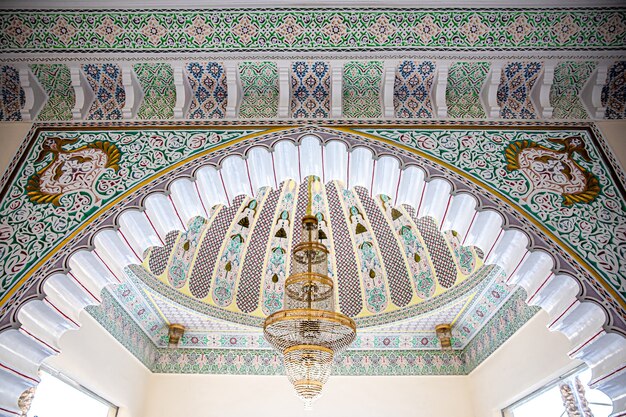 Large golden chandelier on a variegated ceiling with islamic traditional religious ornament