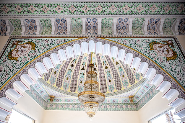 Large golden chandelier on a variegated ceiling with islamic traditional religious ornament