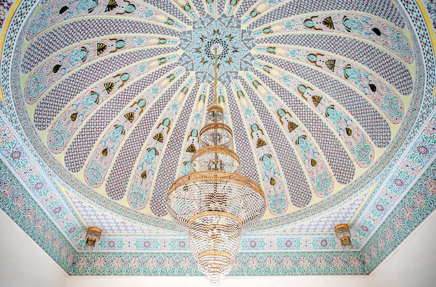 Grande lampadario dorato su un soffitto variegato con ornamento religioso tradizionale islamico.