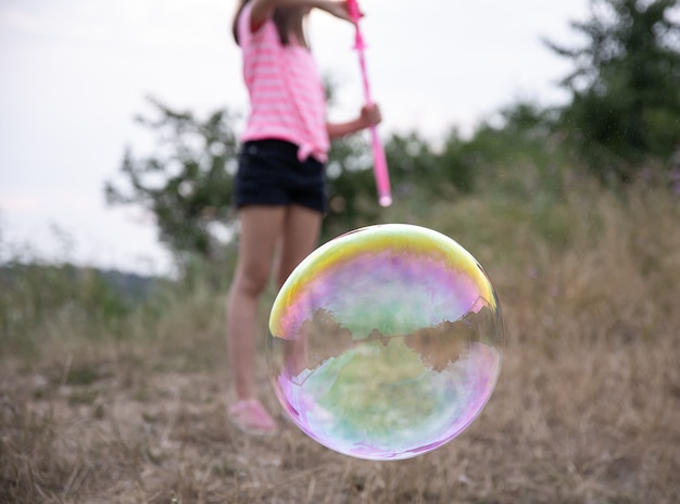 Большой разноцветный мыльный пузырь на размытом фоне.