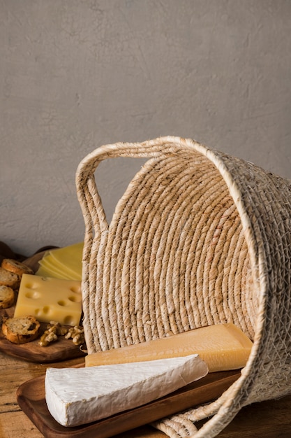 Large piece of cheese on wooden tray in wicker basket