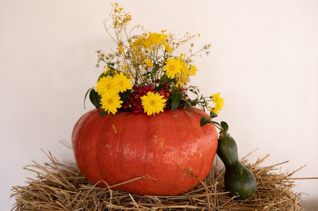 Large pumpkins among straw and flowers, rustic style, autumn harvest.