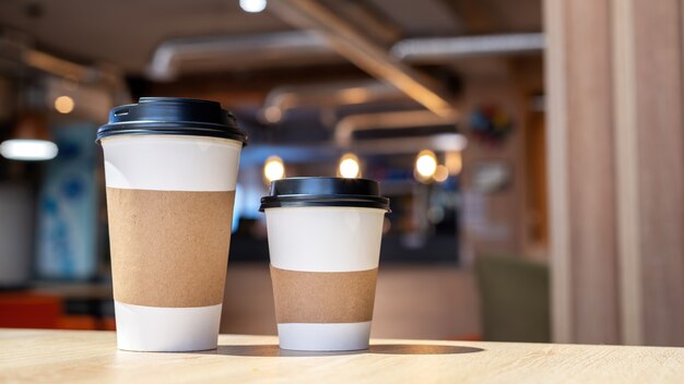 Large and small cup of coffee on a wooden table in a cafe. Recycling idea