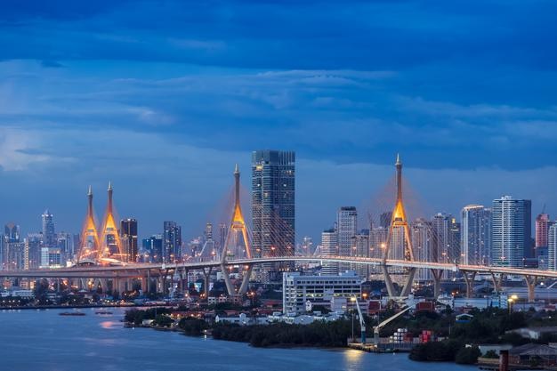 Large suspension bridge over Chao Phraya river at twilight with city in background