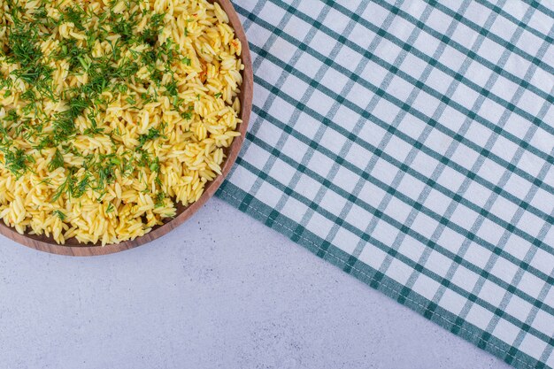 Large tray of cooked brown rice topped with dill on marble background. High quality photo