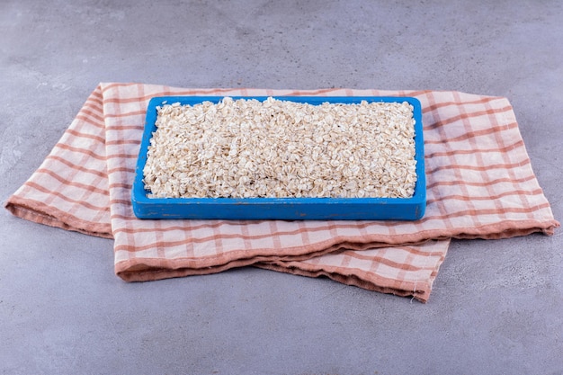 Large tray with oats piled on top, on a towel on marble background. High quality photo