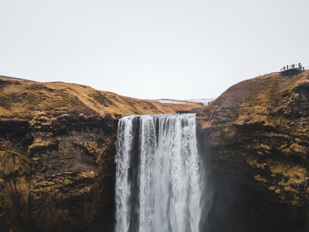 large waterfall streaming down from the dry brown mountain