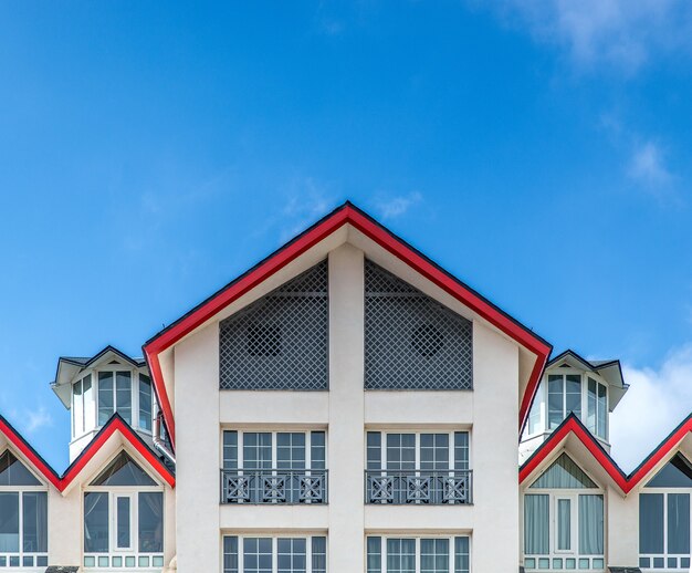 Large white building with red framed roof under a blue sky