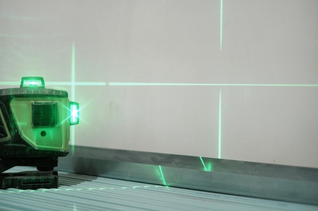 Laser measuring level for construction work, during work, shallow depth of field. Green laser beams for level measurement. Construction and finishing works