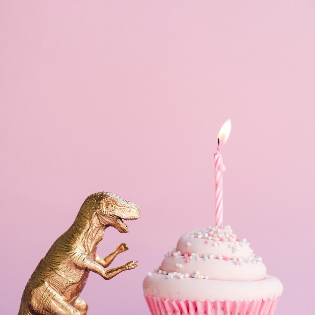 Боковой вид на день рождения торт и пластиковый динозавр