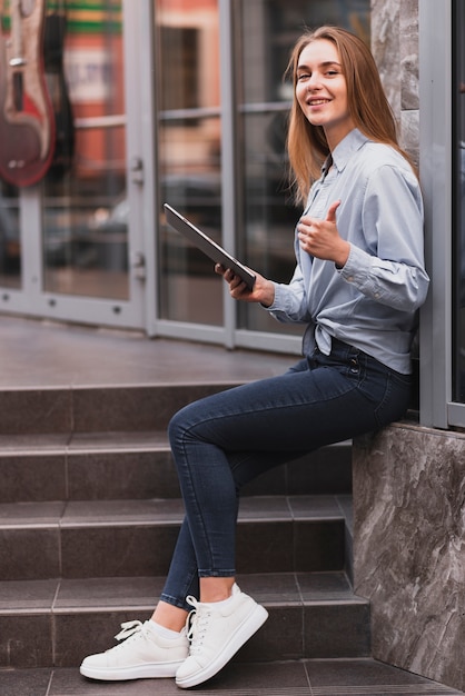 Lateral view blonde girl holding a tablet