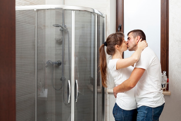 Lateral view couple kissing in bathroom