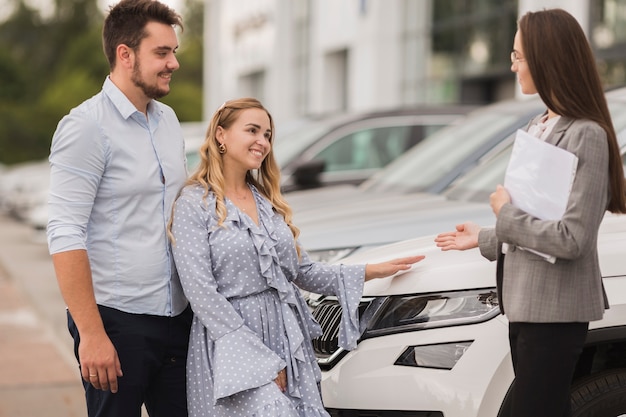 Lateral view couple talking with female car dealer
