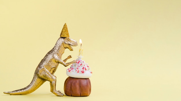 Vista laterale dinosauro e muffin compleanno