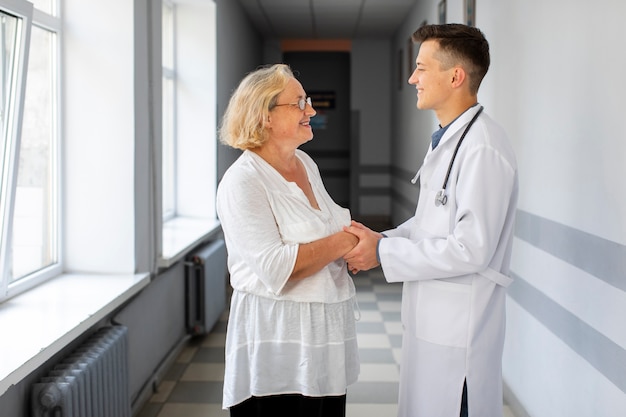 Free photo lateral view doctor holding hands of patient