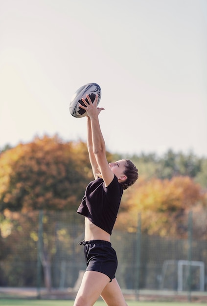 Foto gratuita ragazza di vista laterale che prende una palla di rugby