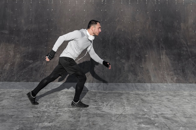 Free photo lateral view handsome man running outside