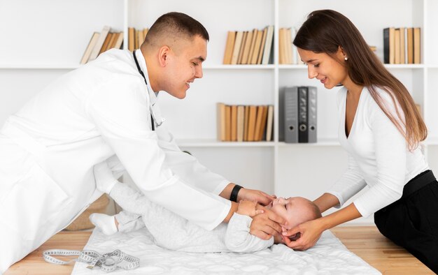 Lateral view smiling doctor looking at baby patient