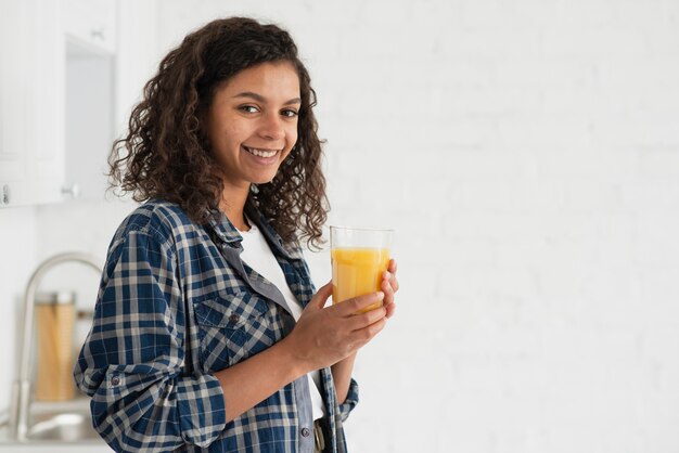 オレンジジュースを飲む女性を笑顔の側面図